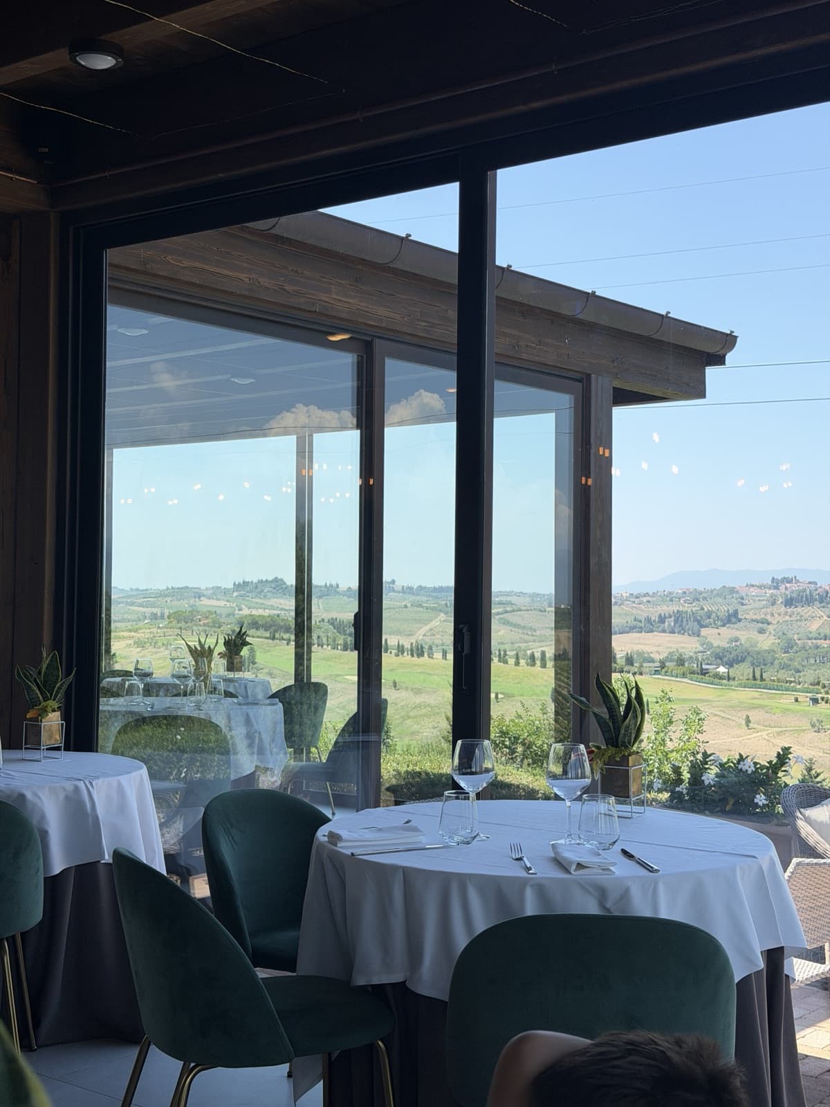 A corner of the dining room, a laid table beside a sliding glass door opening onto the terrace and the valley