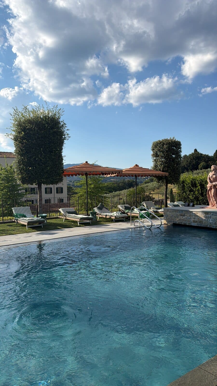 The pool in the evening with umbrellas, statue and hills under a big sky