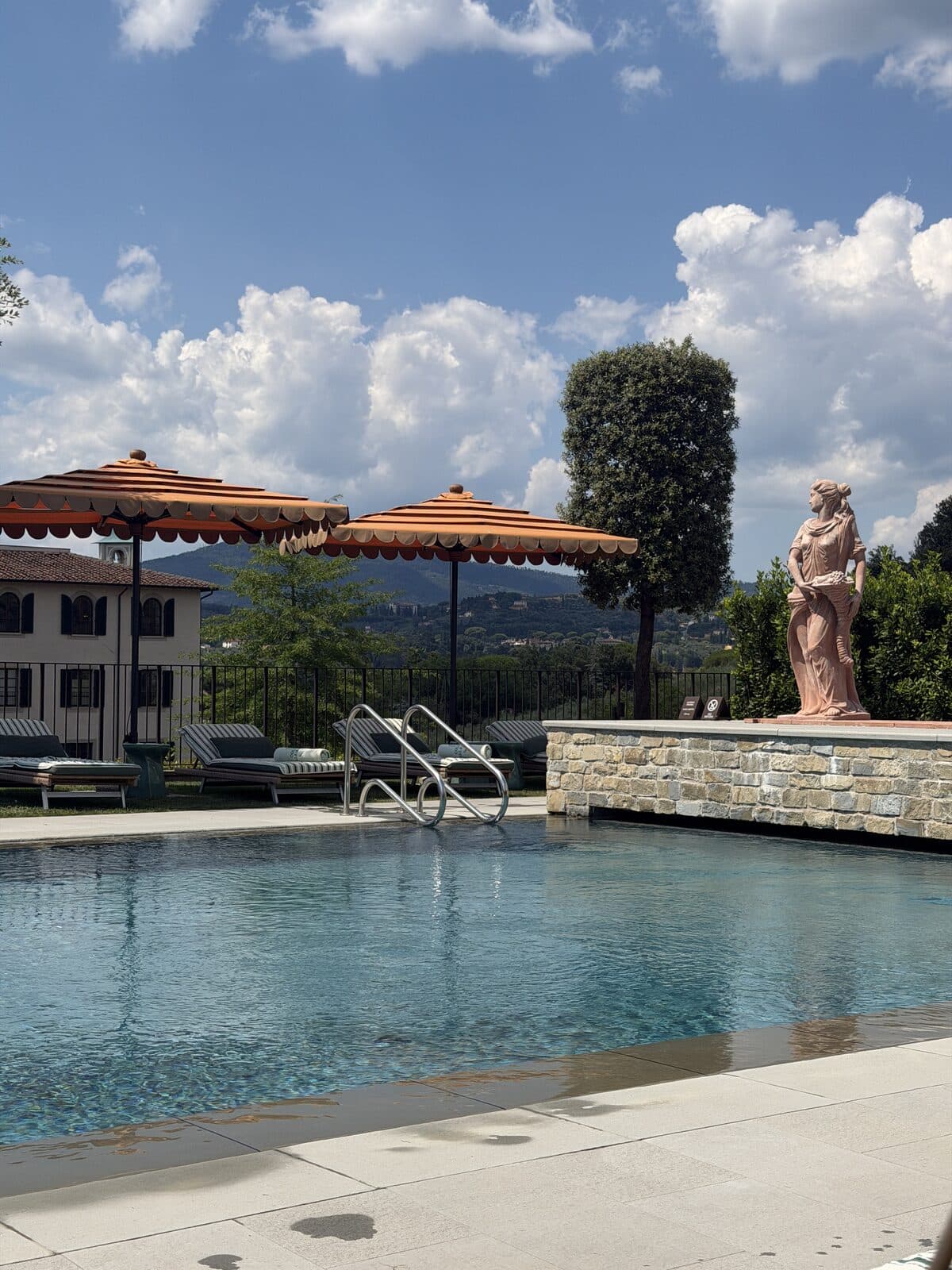 Terracotta statue beside the pool with Tuscan hills in the distance