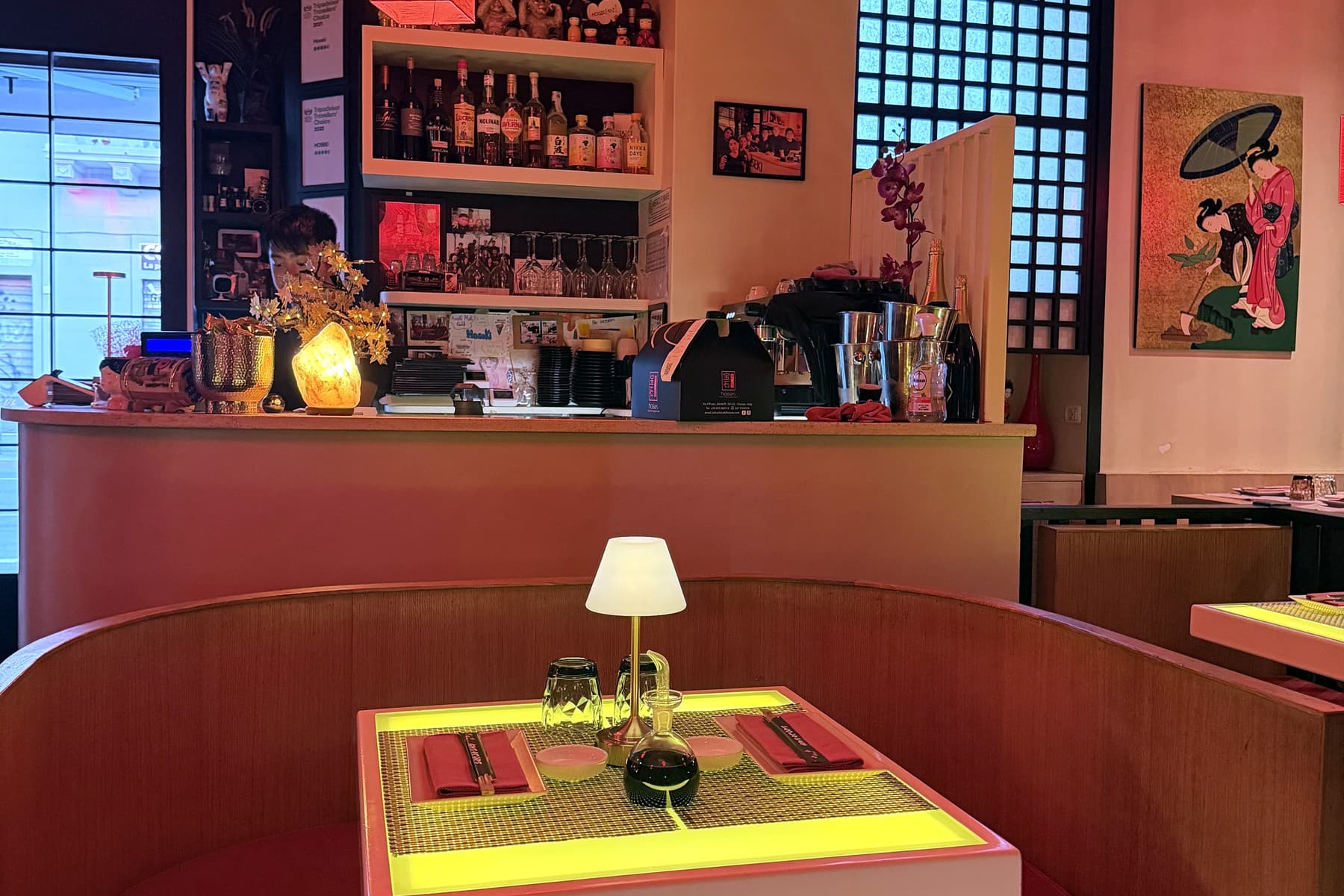 A booth at Hoseki with a lit table and the bar behind, under the room's red light