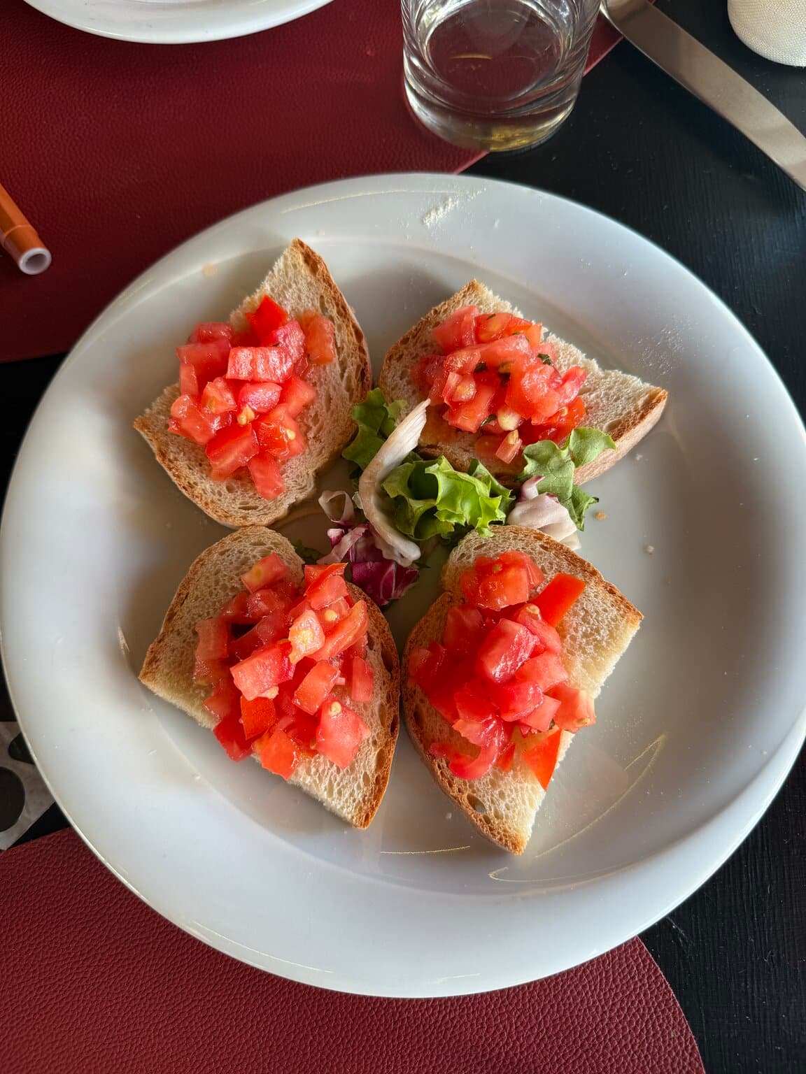Four bruschette topped with fresh tomato