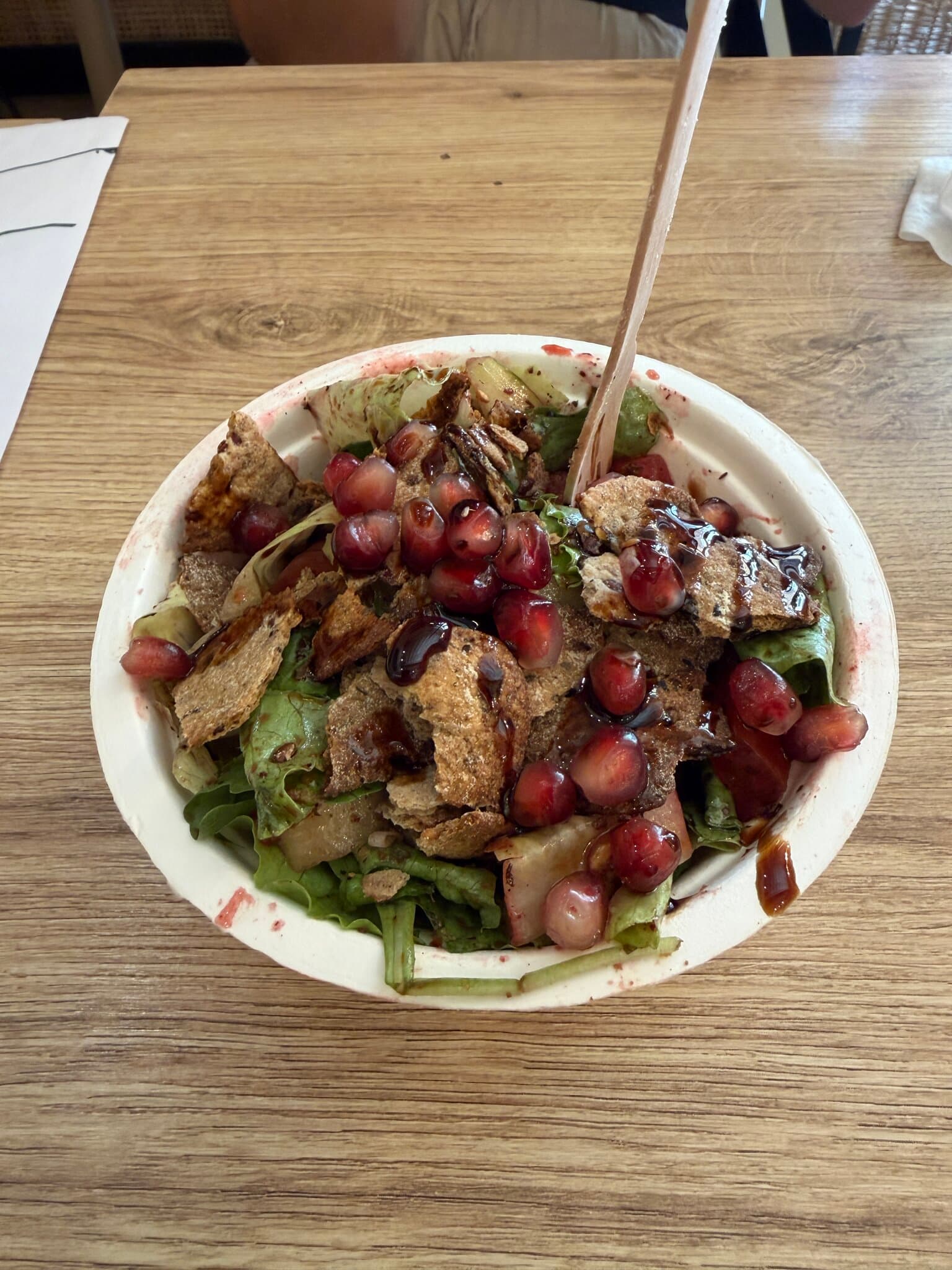 Fattoush salad topped with pomegranate seeds, crackers and molasses