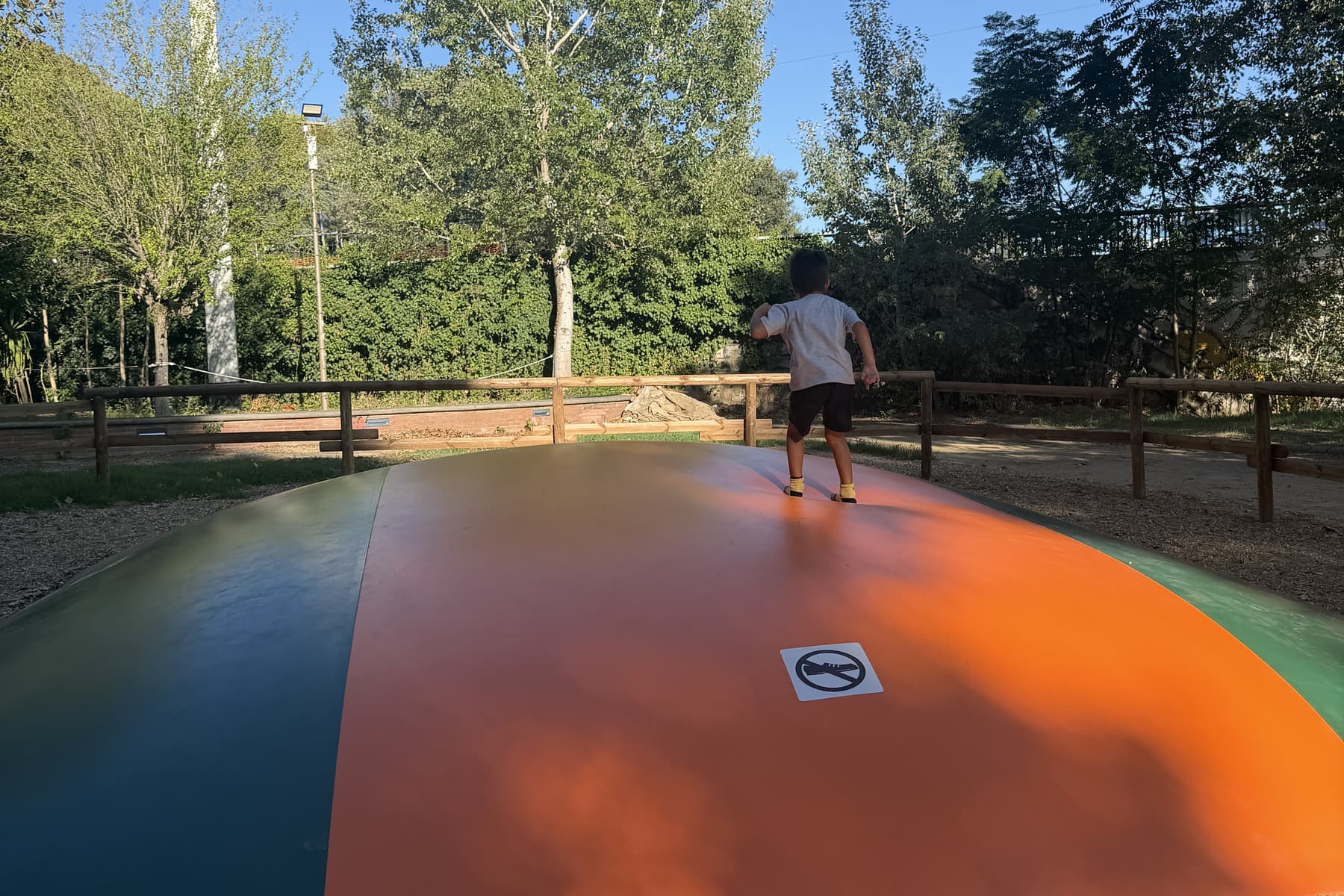 An adult standing on a large orange inflatable jumping pillow