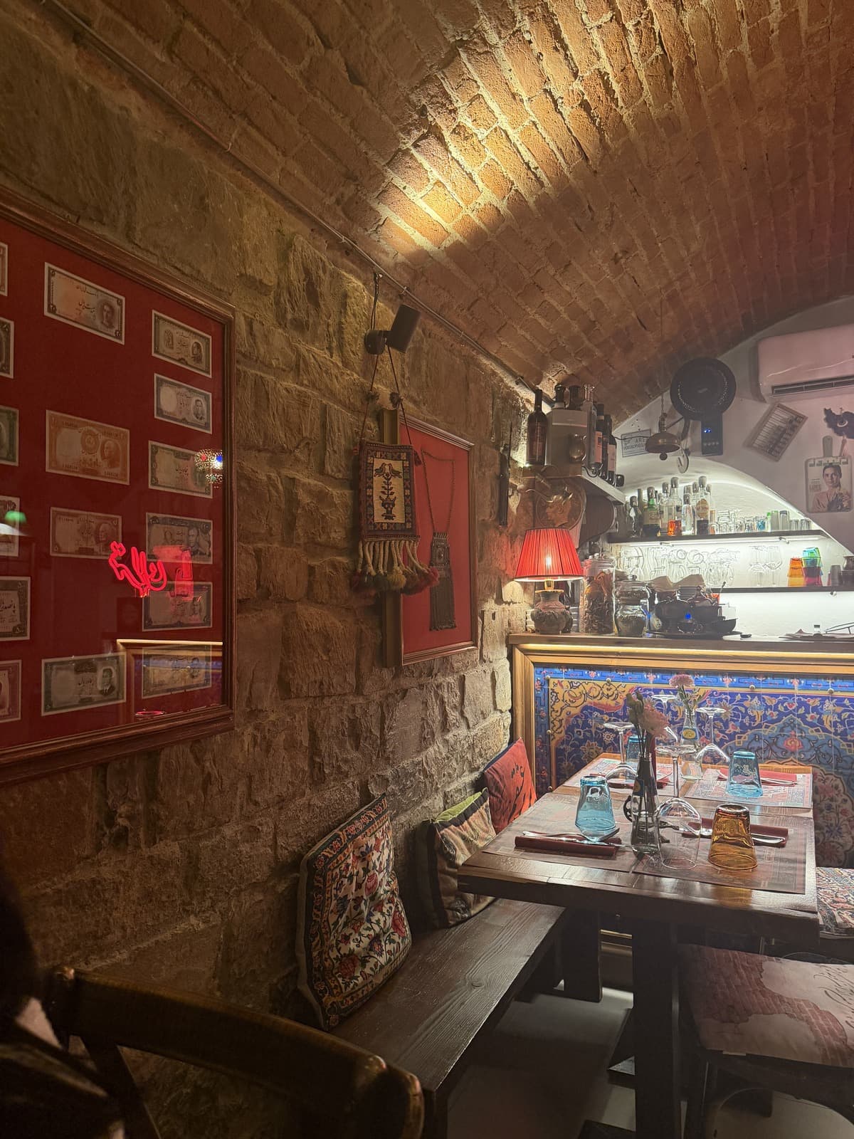 The dining room at Tehran under a brick barrel vault, red walls, Persian tiles and a lit table