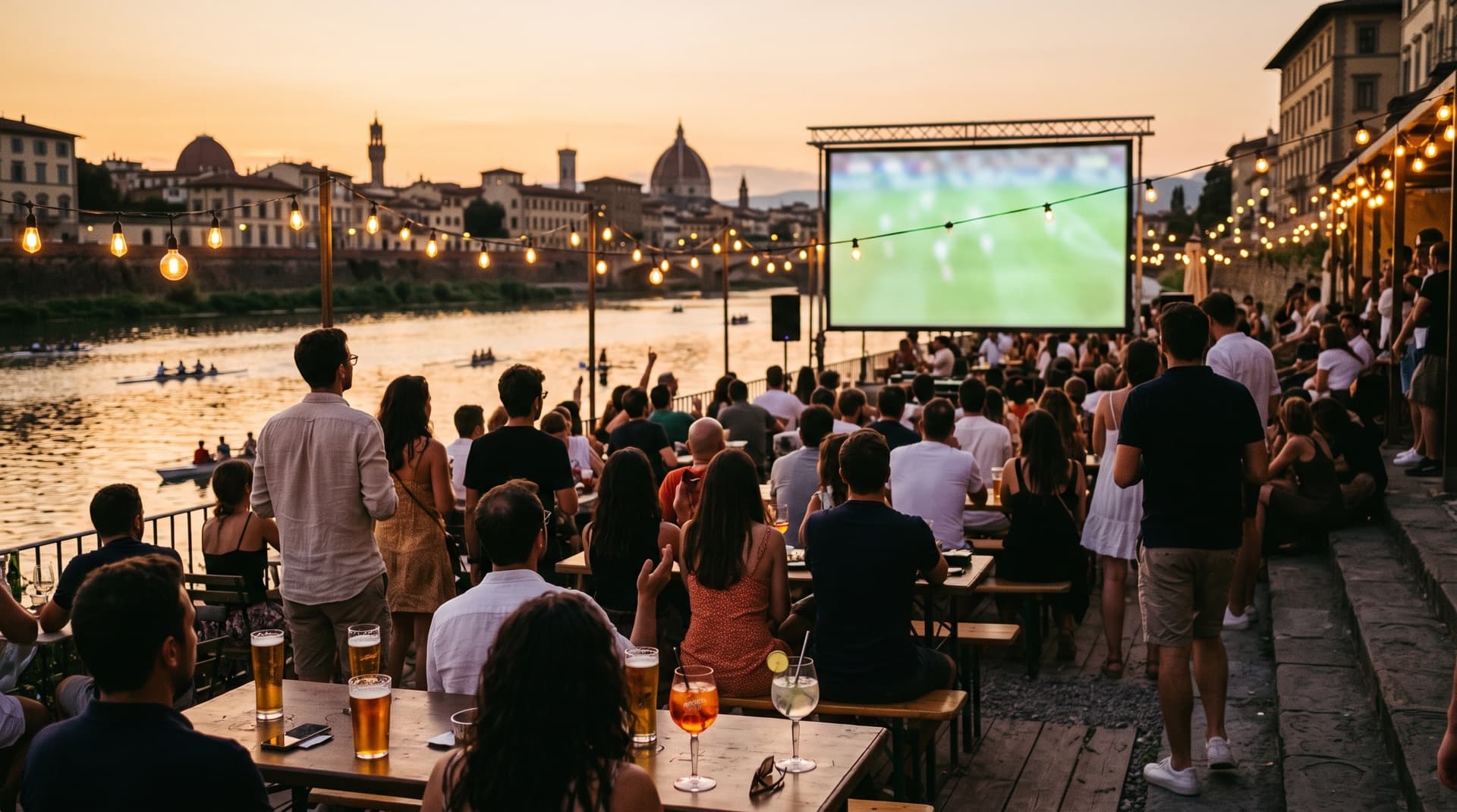 Crowd watching football on an outdoor screen by the Arno on a summer evening