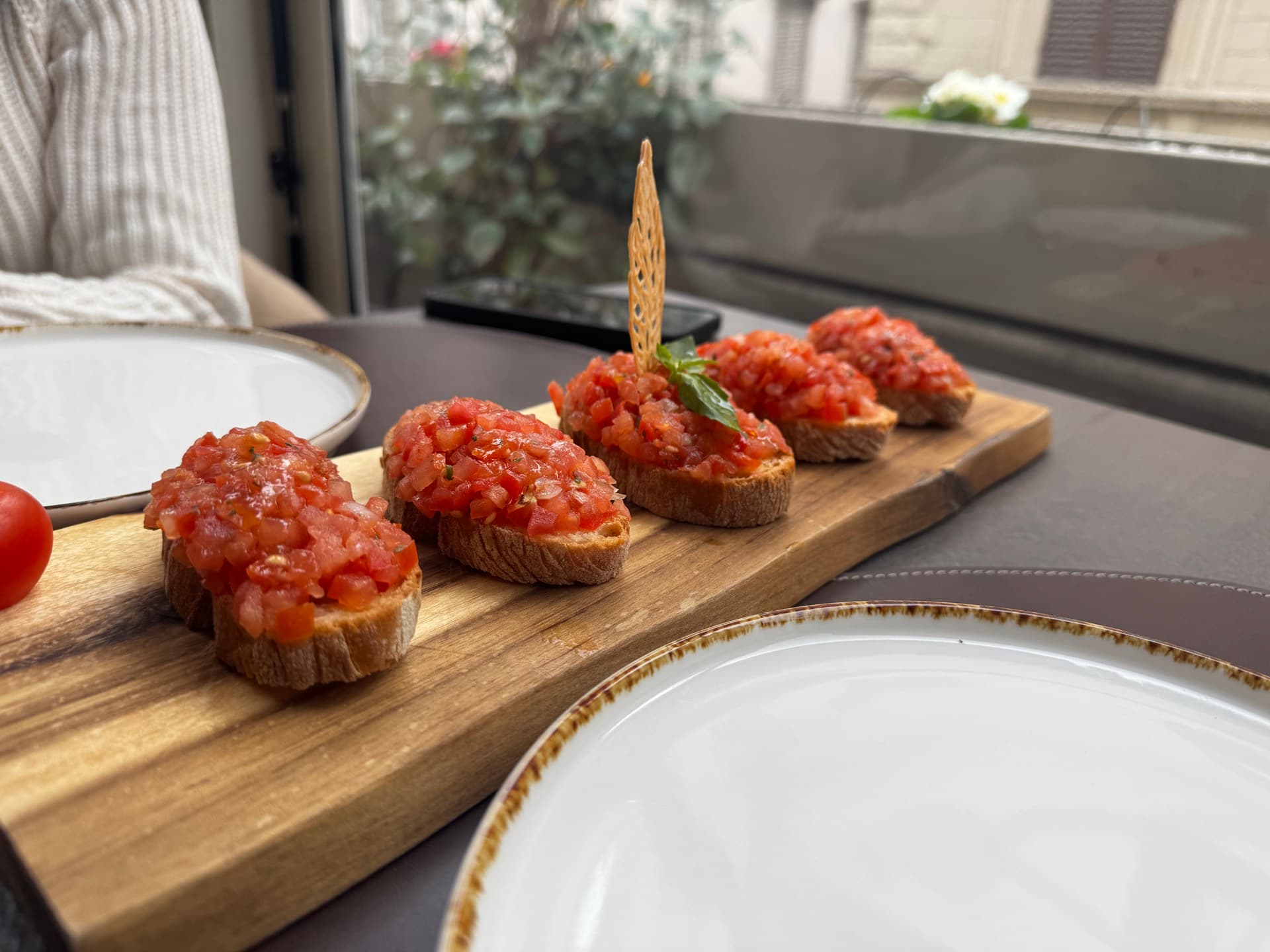 Tomato crostini on a wooden board at a Florence restaurant table by a window